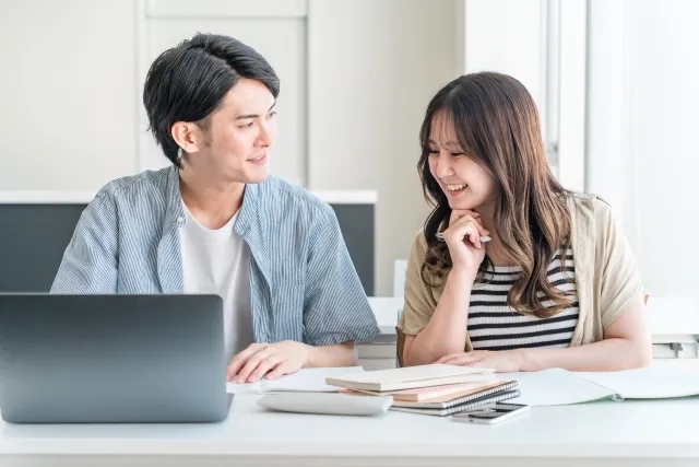 ノートパソコンを前に話し合う学生